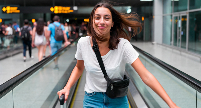 Soggiorni linguistici con LISA! – viaggio, aeroporto e inizio dell’avventura Giovane donna con valigia in aeroporto durante un soggiorno linguistico LISA! entusiasta per l’arrivo