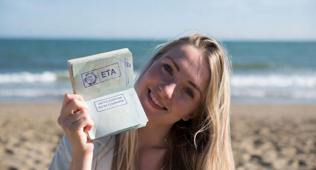 Soggiorni linguistici in Inghilterra con LISA! – ingresso, visto ETA e preparazione Donna sulla spiaggia mostra il passaporto con autorizzazione ETA durante un soggiorno linguistico LISA! in Inghilterra