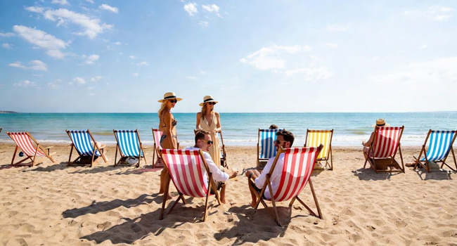  Partecipanti adulti che si rilassano su sdraio sulla spiaggia di Bournemouth durante un soggiorno linguistico LISA! in Inghilterra