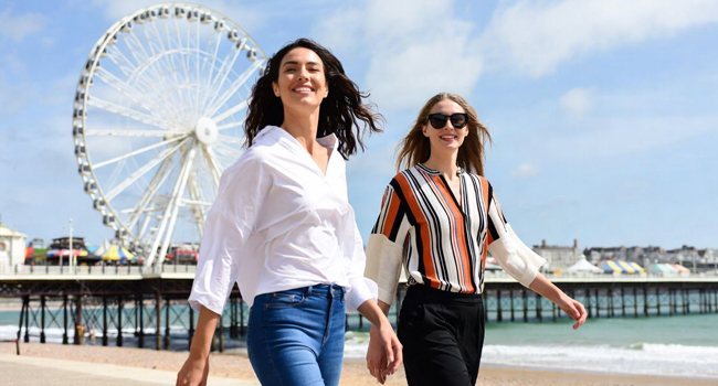 Due partecipanti che passeggiano sul lungomare di Bournemouth con la ruota panoramica durante un soggiorno linguistico LISA! in Inghilterra