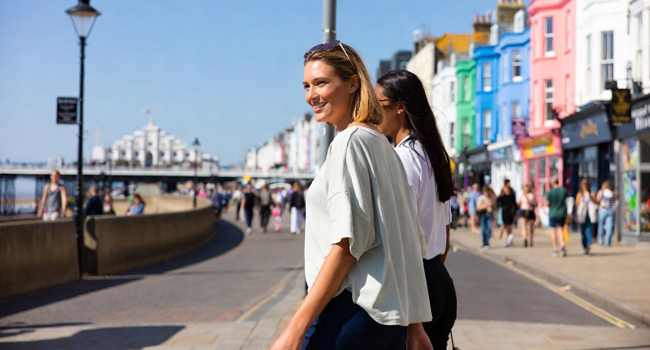 Soggiorni linguistici per adulti in Inghilterra Brighton con LISA! – lungomare, città e mare Partecipanti che passeggiano sul lungomare di Brighton con case colorate durante un soggiorno linguistico LISA! in Inghilterra