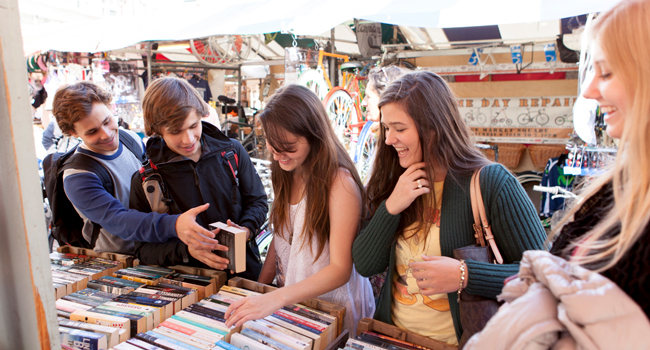  Adulti che fanno shopping in un mercato a Cambridge City Inghilterra durante un soggiorno linguistico LISA! guardano libri e si divertono