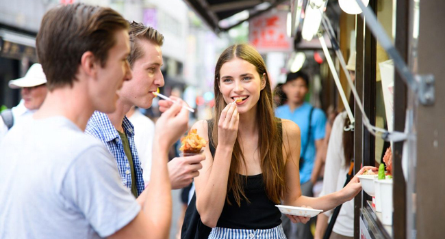 Congedo formativo Osaka Giappone con LISA! – imparare il giapponese, street food ed esperienze autentiche Adulti assaggiano street food a Osaka durante un congedo formativo LISA! scoprono la cucina giapponese e la vita urbana internazionale