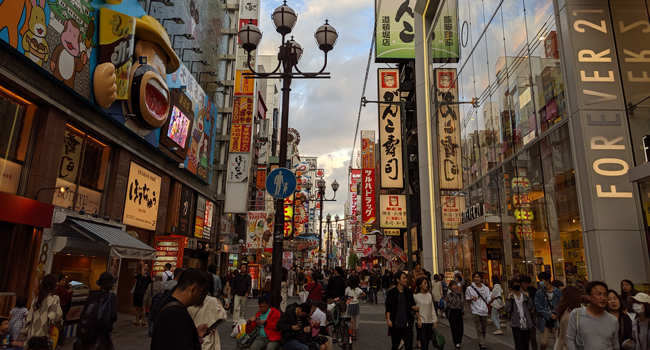 Congedo formativo Osaka Giappone con LISA! – imparare il giapponese, città ed esperienze autentiche Strada animata a Osaka durante un congedo formativo LISA! con cultura giapponese, luci al neon e vita urbana