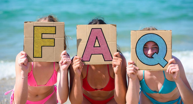 FAQ soggiorni linguistici LISA! – risposte alle domande frequenti Tre studentesse sulla spiaggia a Bournemouth Park Inghilterra tengono cartelli FAQ durante un soggiorno linguistico LISA!
