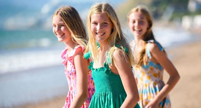 Soggiorni linguistici in Inghilterra Bournemouth con LISA! – spiaggia, estate ed esperienze indimenticabili Tre studentesse sulla spiaggia a Bournemouth Inghilterra durante un soggiorno linguistico LISA! con abiti estivi godono del mare