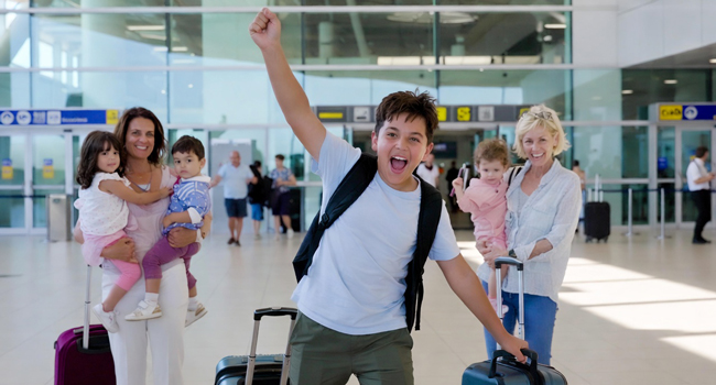 Arrivo per un soggiorno linguistico per studenti in Inghilterra Brighton con LISA! – studente felice in aeroporto Studente in arrivo all’aeroporto con il braccio alzato entusiasta per un soggiorno linguistico LISA! per studenti in Inghilterra Brighton