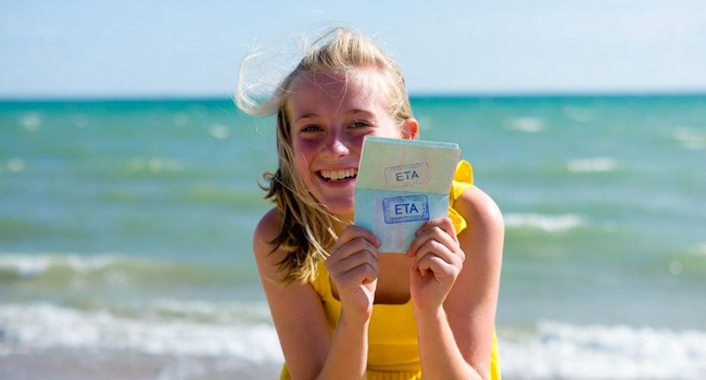 Studentessa sulla spiaggia a Exmouth durante un soggiorno linguistico LISA! mostra documento ETA di ingresso per l’Inghilterra