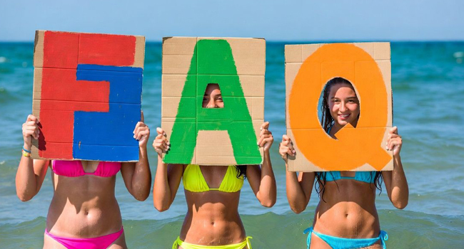 Studentesse sulla spiaggia a Exmouth tengono lettere FAQ durante un soggiorno linguistico LISA! con il mare sullo sfondo