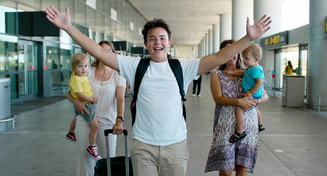 Arrivo per un soggiorno linguistico per studenti con LISA! – studente felice in aeroporto Studente in arrivo all’aeroporto con le braccia alzate entusiasta per un soggiorno linguistico LISA! per studenti