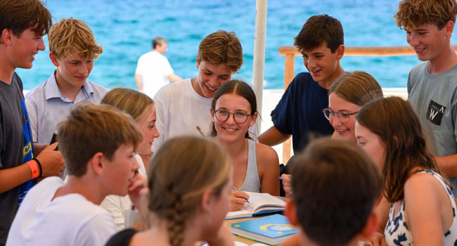 Gruppo di studenti che studiano insieme vicino al mare durante un soggiorno linguistico LISA! per studenti a Malta
