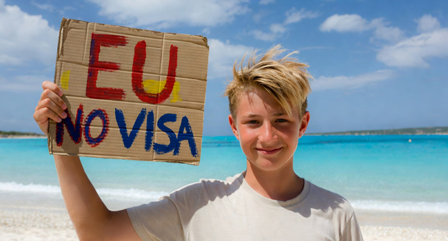 Studenti di un soggiorno linguistico di inglese a Malta sulla spiaggia con un cartello sull’ingresso senza visto per i cittadini dell’UE