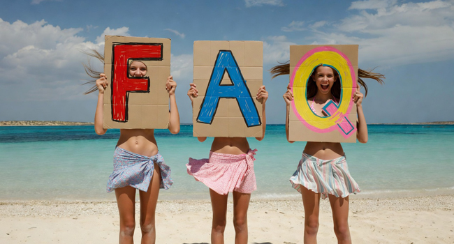 Tre studentesse di un soggiorno linguistico per studenti a Malta a Salina Beach con grandi lettere FAQ davanti al mare