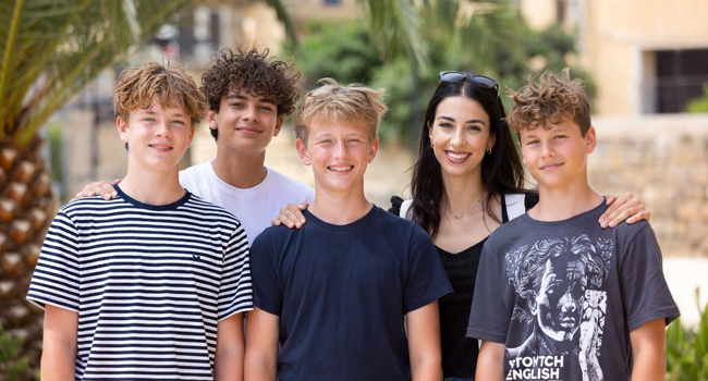 Assistenza durante un soggiorno linguistico per studenti a Malta San Gwann Responsabile e insegnante con quattro ragazzi davanti a una palma durante un soggiorno linguistico a Malta San Gwann
