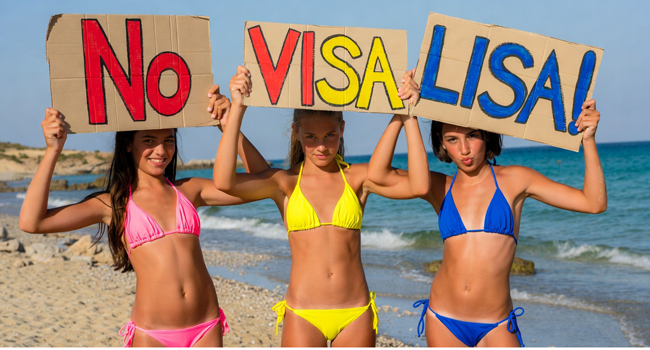 Nessun visto per Malta con LISA! soggiorni linguistici – studentesse con cartelli sulla spiaggia Tre studentesse sulla spiaggia a Malta tengono cartelli “No Visa LISA!” durante un soggiorno linguistico LISA! per studenti