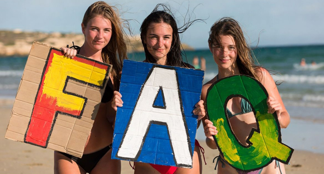 FAQ sui soggiorni linguistici per studenti a Malta con LISA! – studentesse con lettere sul mare Tre studentesse sulla spiaggia a Malta tengono grandi lettere FAQ durante un soggiorno linguistico LISA! per studenti