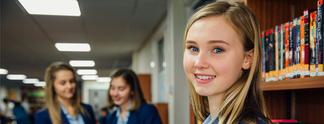 Mädchen sind in der Bibliothek einer Schule und lesen während eines High School Year