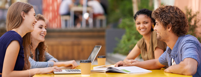 Vier Erwachsene sitzen an einem Tisch mit Tablets und lernen gemeinsam