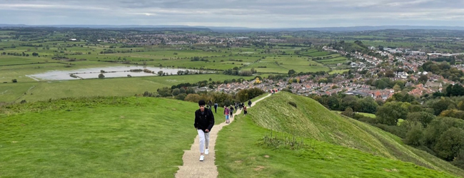Mehrere Personen steigen auf einen Hügel mit Blick auf Exeter und die Landschaft in Devon