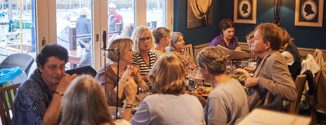 Viele Personen sitzen gemeinsam in einem Restaurant und essen bei einer Sprachreise in Jersey