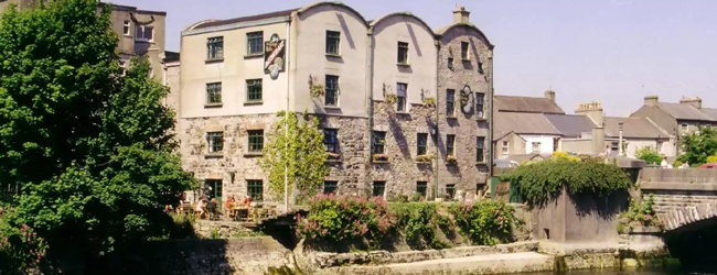 Historisches Gebaeude am Fluss in Galway mit Bäumen