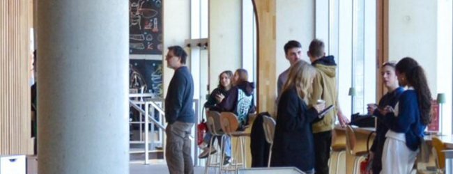 Schüler des Französisch-Sprachkurses unterhalten sich in der Pause in einer modernen Lounge