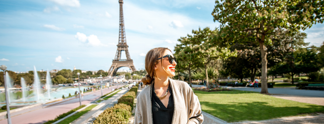 Eine junge Frau mit Sonnenbrille geht durch den Park am Eiffelturm bei einer LISA! Sprachreise in Paris