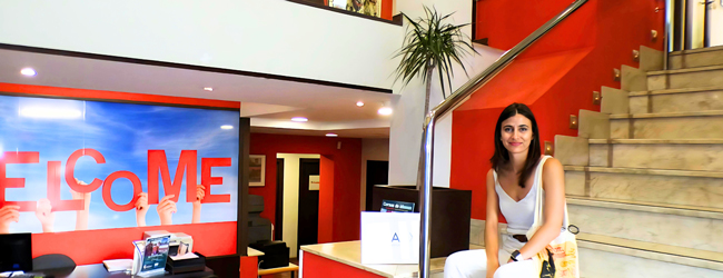 Eine Frau sitzt lächelnd auf der Treppe in der Lobby der LISA! Sprachschule in Palma de Mallorca