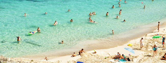 Mehrere Menschen baden im Meer oder sonnen sich am Strand auf Mallorca