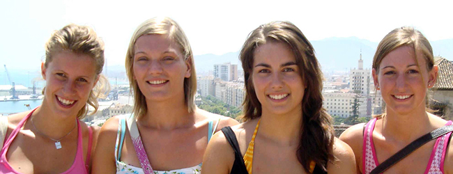 Vier Mädchen lächeln in die Kamera im Hintergrund der Hafen von Malaga