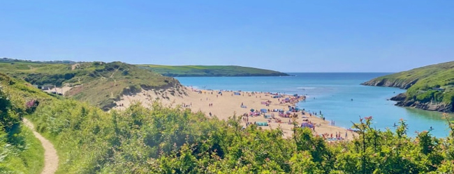 Bucht in Cornwall von einem Wanderweg aus gesehen Blick vom Crantock Coast Path in Corwall auf eine Bucht am Meer mit Badenden