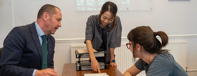 Eine Lehrerin erklärt zwei Erwachsenen etwas bei einer LISA! Sprachreise für Familien in London