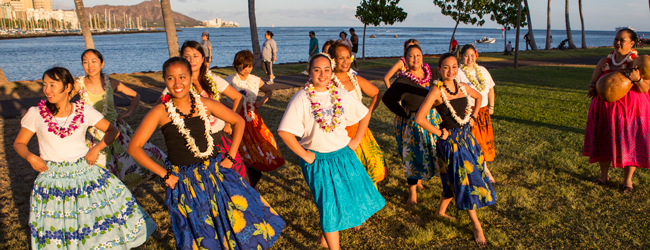 Hula-Tanz bei einer Sprachreise für Familien auf Hawaii Mehrere Damen tanzen am Meer auf Hawaii in Röcken Hula bei einer LISA! Sprachreise in Honolulu