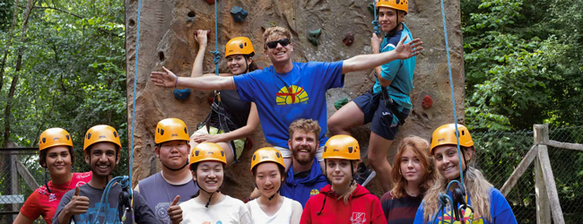Schüler mit gelbem Helm stehen vor einer Kletterwand bei einer LISA! Sprachreise
