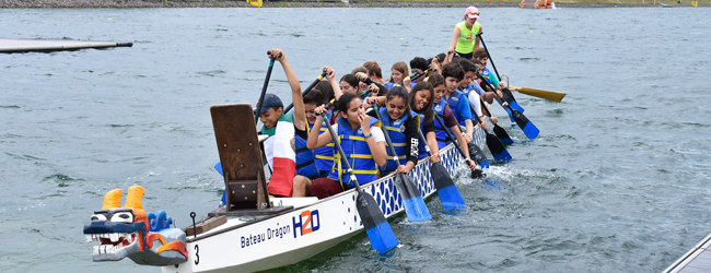 Eine Gruppe Jugendlicher fährt auf einem Fluss Kanu mit blauen Warnwesten bei einer Sprachreise