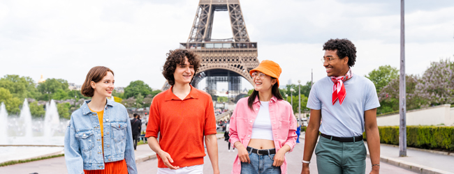 Vier junge Leute stehen vor dem Eiffelturm bei einer LISA! Sprachreise in Paris